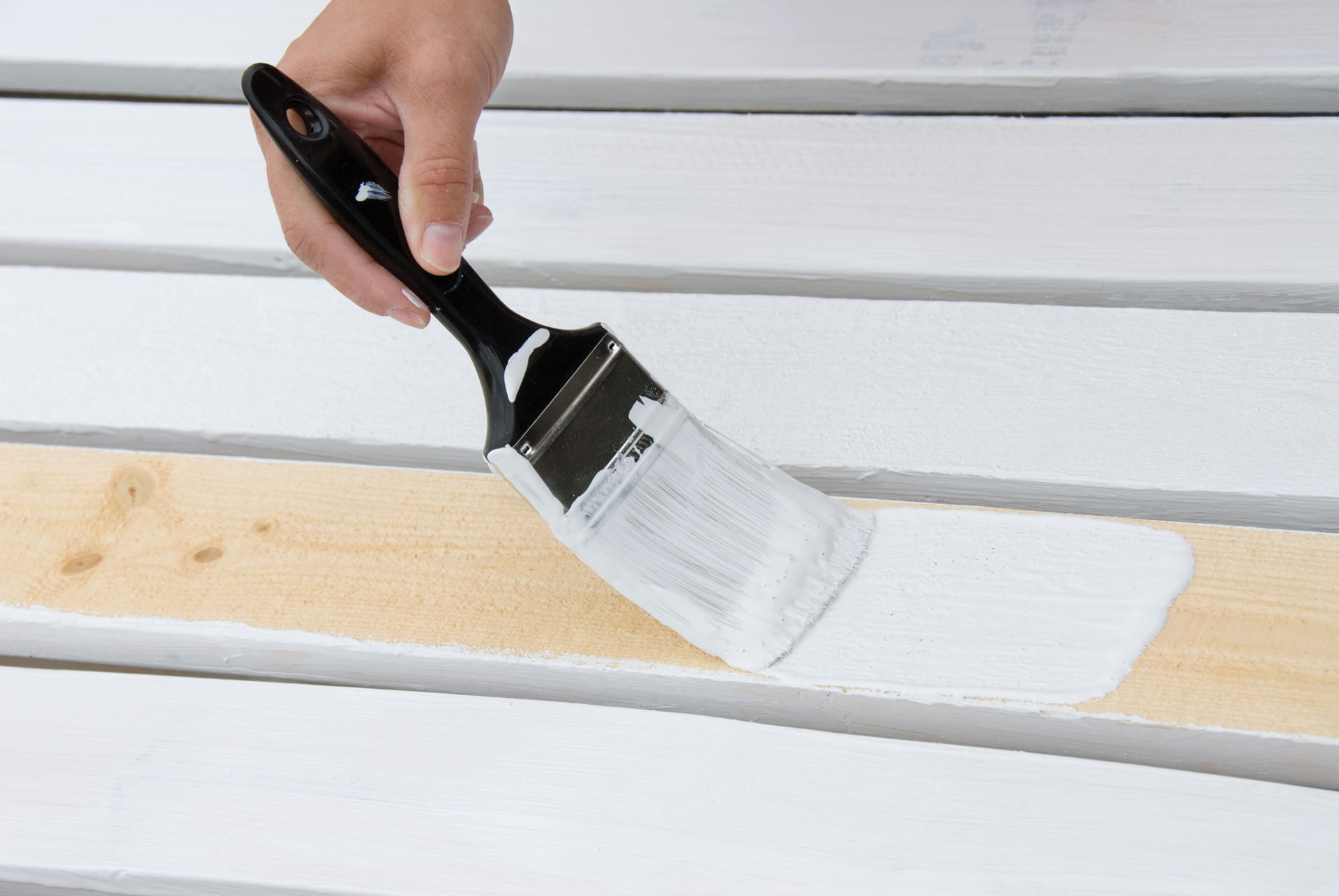 Hand painting wooden deck slats with white paint. Hand painting wooden deck slats with white paint.